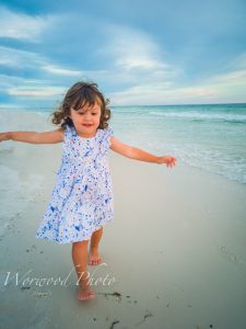 little girl running on white sandy florida beach, crystal clear blue water